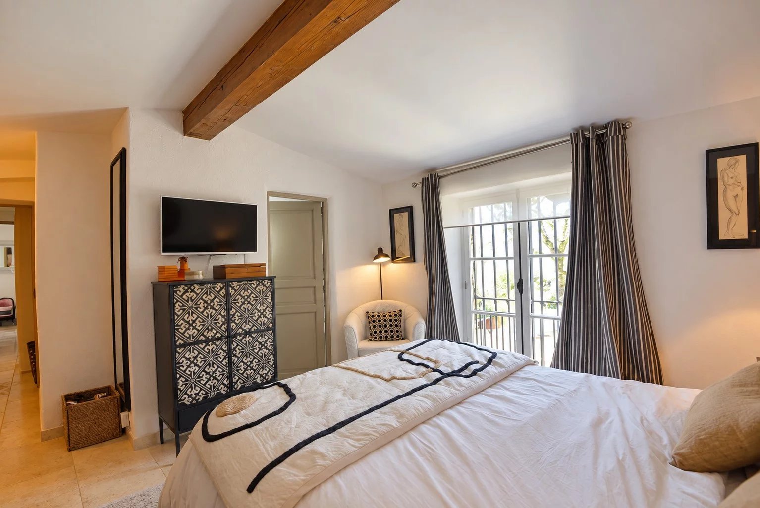 Chambre d'une maison en pierre à Tourrettes, avec lit, meuble et fenêtre donnant sur l'extérieur.