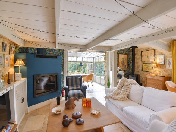 Intérieur d'une maison en pierre avec salon lumineux et cheminée.