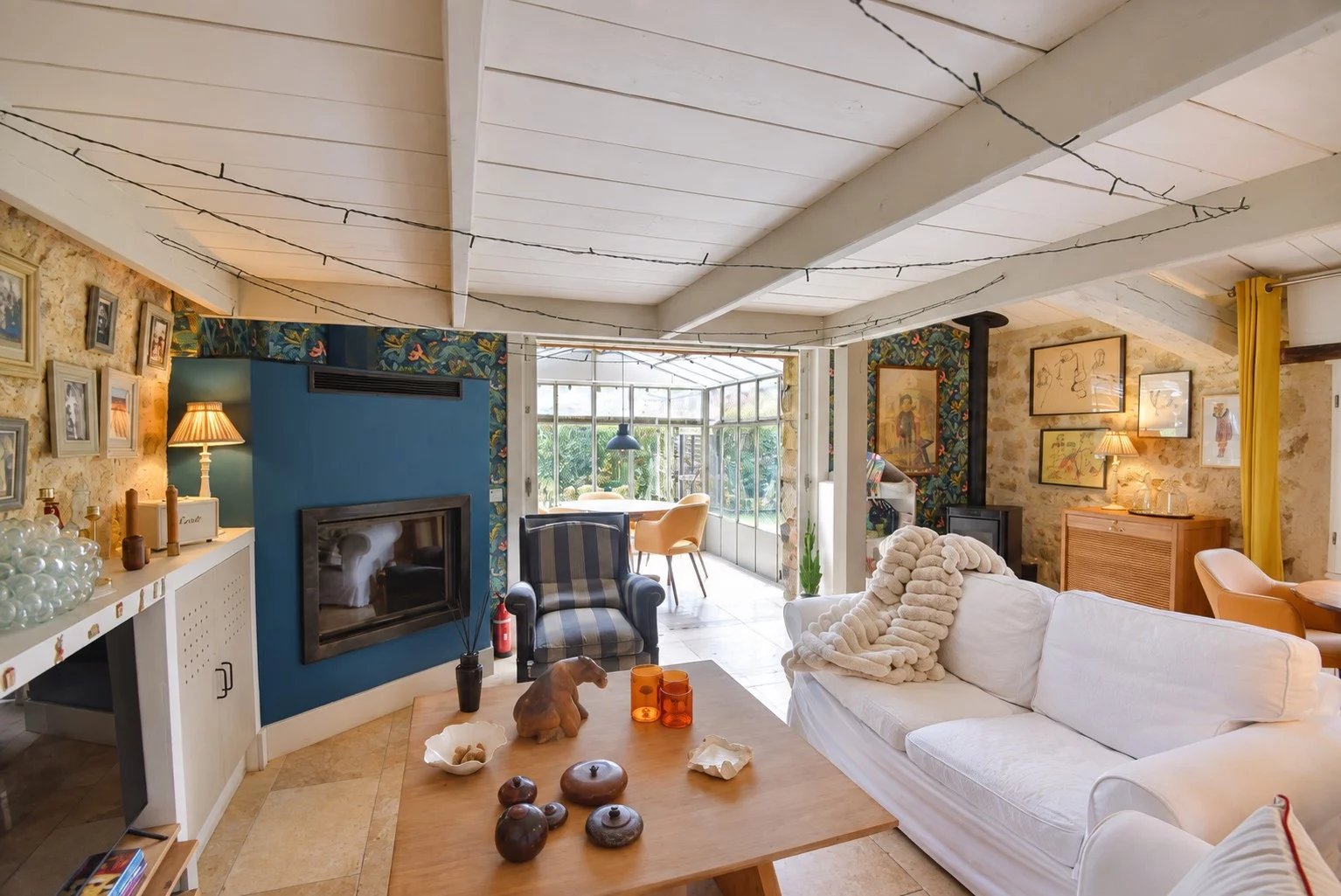 Intérieur d'une maison en pierre avec salon lumineux et cheminée.