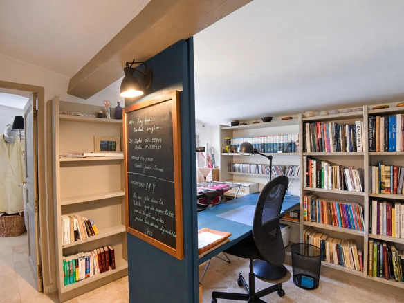 Intérieur d'une maison en pierre avec bureau et étagères à Tourrettes, France.