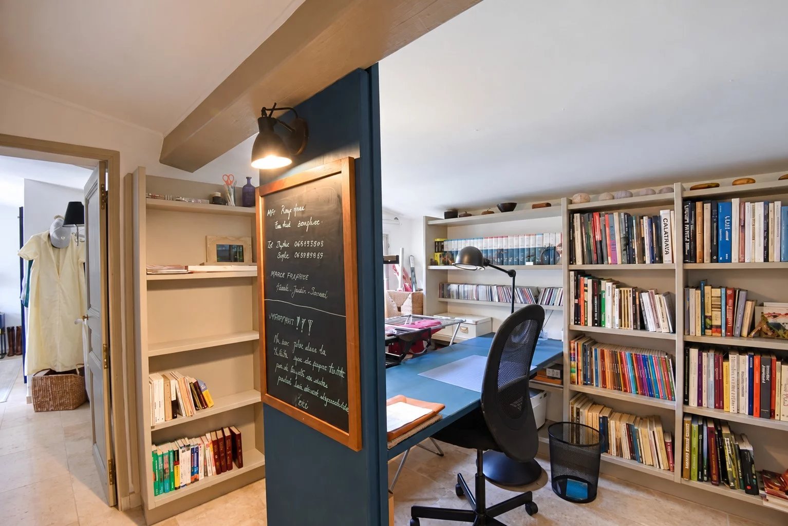 Intérieur d'une maison en pierre avec bureau et étagères à Tourrettes, France.