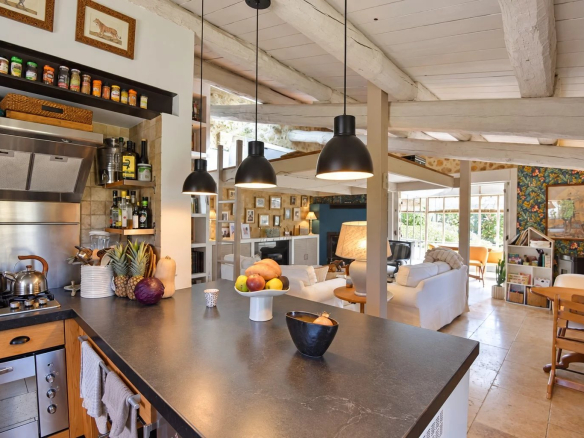 Intérieur d'une maison en pierre avec cuisine ouverte et salon lumineux à Tourrettes.