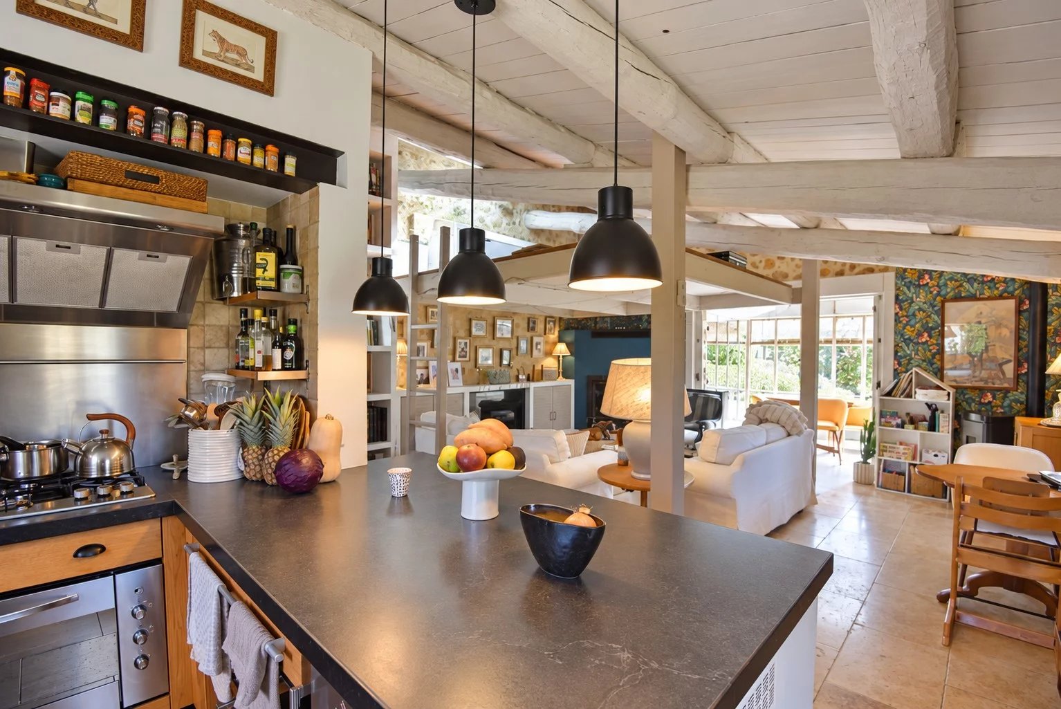 Intérieur d'une maison en pierre avec cuisine ouverte et salon lumineux à Tourrettes.