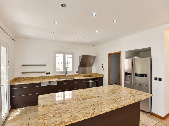 Cuisine moderne avec plan de travail en granit et appareils électroménagers en inox dans une villa provençale.
