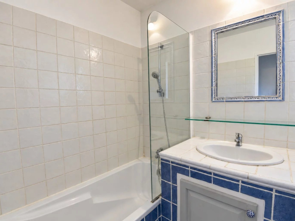 Salle de bain avec baignoire et douche en verre, carrelage beige et bleu