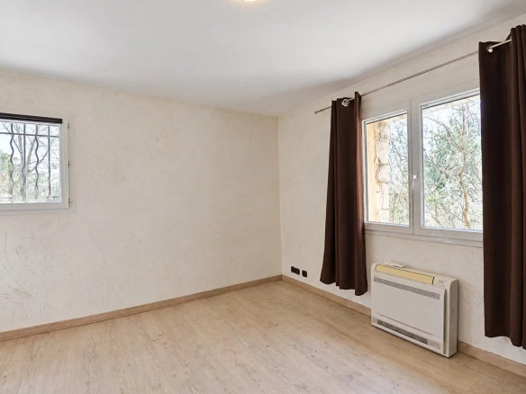 Intérieur d'une villa provençale avec fenêtres et rideaux, sol en bois.