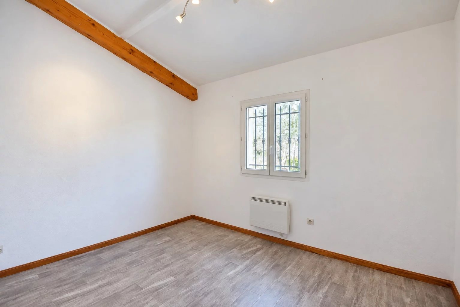 Intérieur d’une villa provençale à Fayence Intérieur d'une pièce vide avec des murs blancs et un sol en parquet, lumière naturelle par la fenêtre.