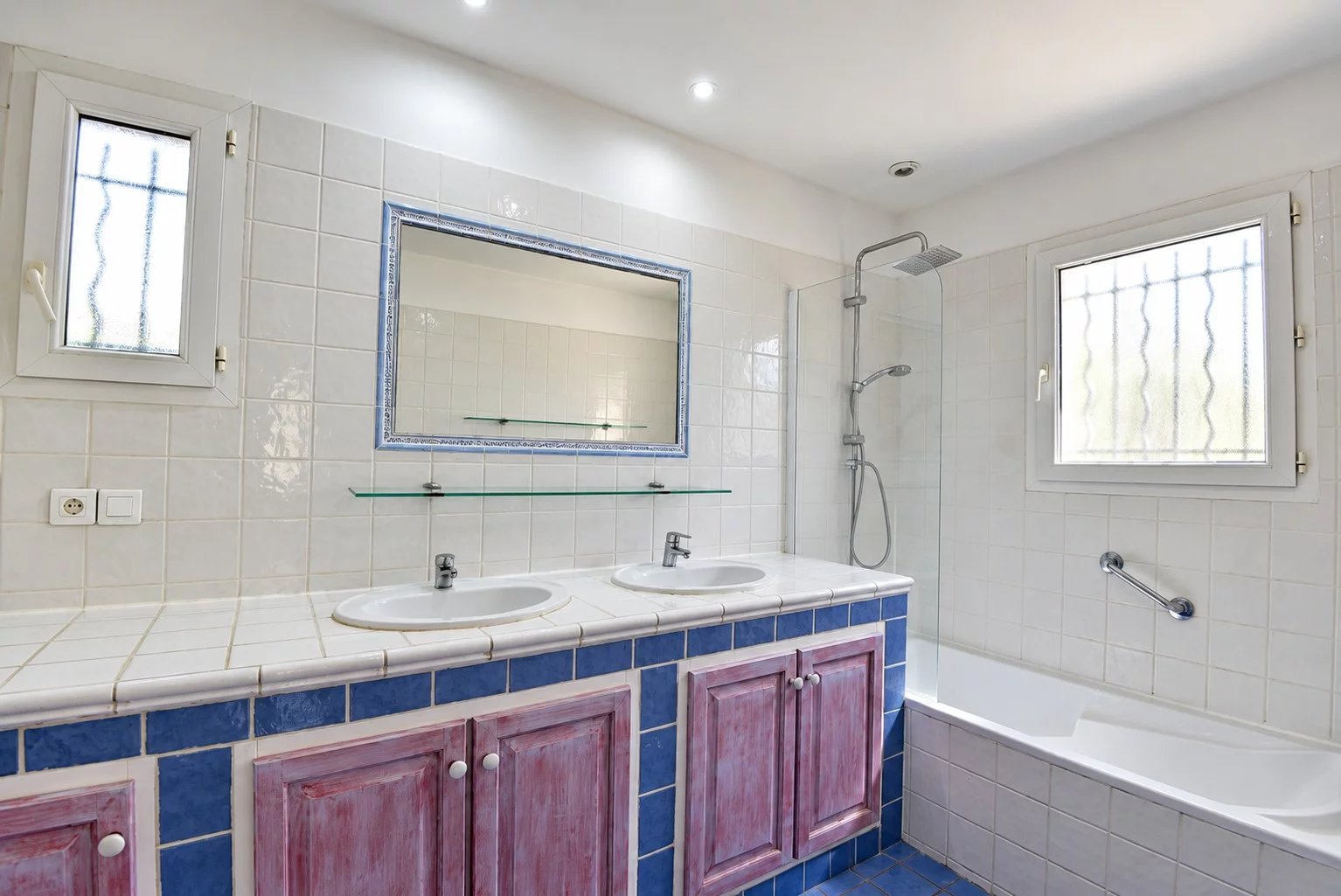 Salle de bain de la villa provençale à Fayence Salle de bain avec deux lavabos, douche et baignoire, carrelage en faïence blanche et bleue.