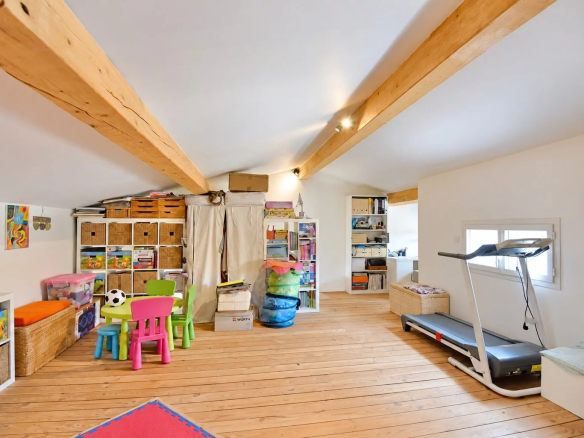 Intérieur d'une villa avec poutres apparentes, espace de jeux et équipements de sport.