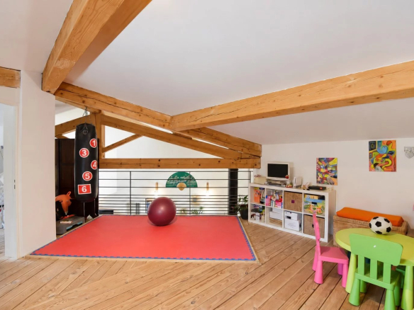 Intérieur d'une villa à Saint-Paul-en-Forêt avec poutres apparentes et espace de jeux.