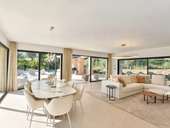 Intérieur d'une villa contemporaine avec salon lumineux et espace repas, ouvert sur le jardin.