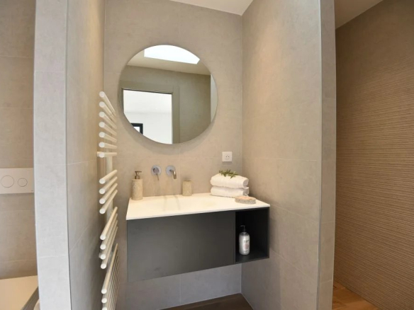Salle de bain moderne avec miroir rond et lavabo dans une villa contemporaine.