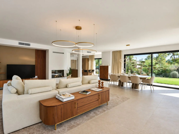Intérieur d'une villa contemporaine avec salon, salle à manger et grandes baies vitrées donnant sur le jardin.