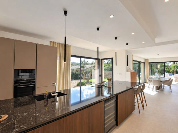 Cuisine moderne avec îlot central dans une villa contemporaine à Tourrettes, vue sur le jardin.