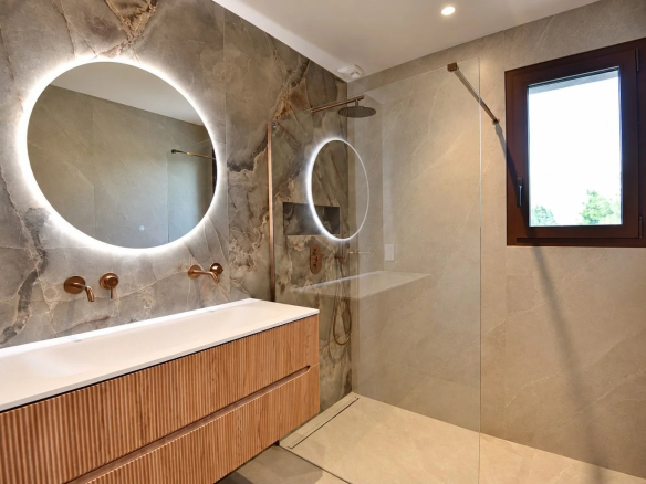 Salle de bain moderne avec douche en verre et double vasque en bois.