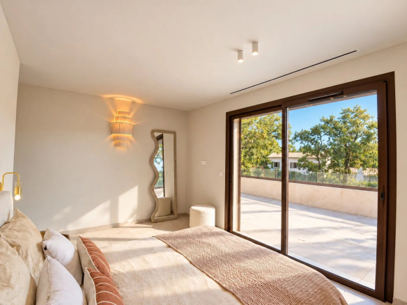 Chambre d'une villa moderne avec accès à une terrasse ensoleillée.
