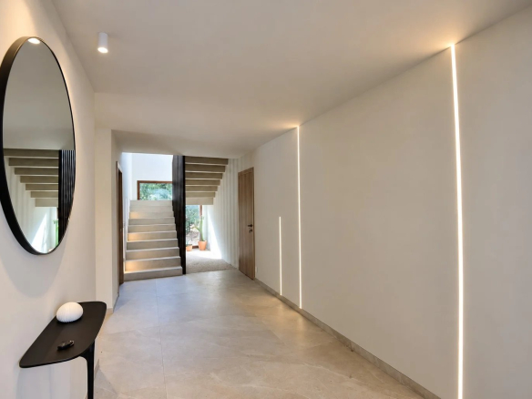 Intérieur d'une villa contemporaine avec un hall d'entrée lumineux et un escalier.