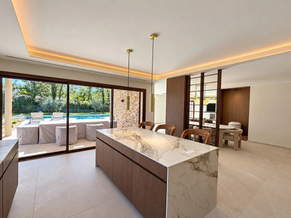 Intérieur d'une villa contemporaine avec cuisine ouverte et vue sur la piscine.