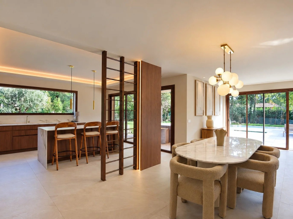 Intérieur d'une villa contemporaine avec cuisine et salle à manger, ouverte sur le jardin.