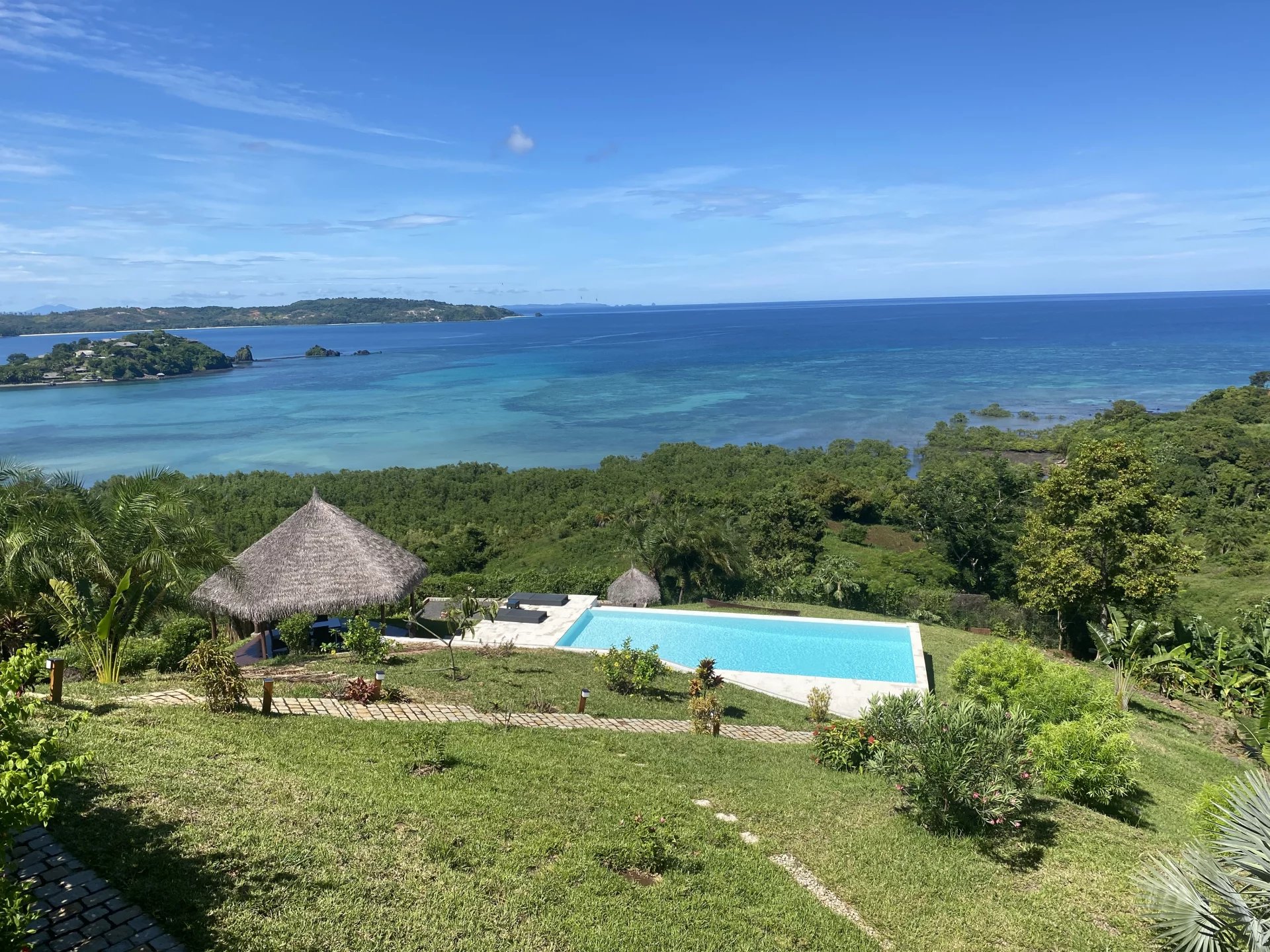 Villa avec vue océan à Nosy Be Vue panoramique sur l'océan depuis une villa avec piscine et jardin à Nosy Be, Madagascar.