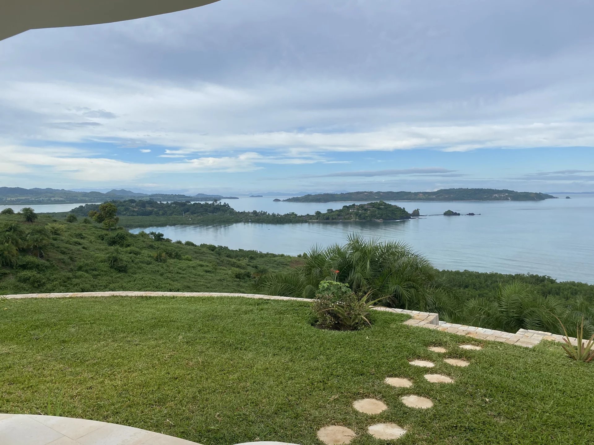 Villa avec vue océan à Nosy Be Vue panoramique sur l'océan depuis une villa à Nosy Be, Madagascar, avec un jardin verdoyant au premier plan.