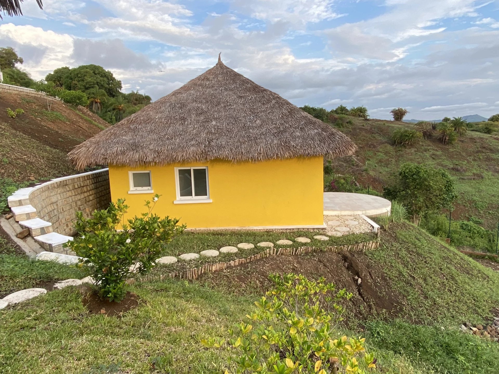 Villa à vendre à Nosy Be Villa jaune avec toit en chaume sur terrain verdoyant à Nosy Be, Madagascar.