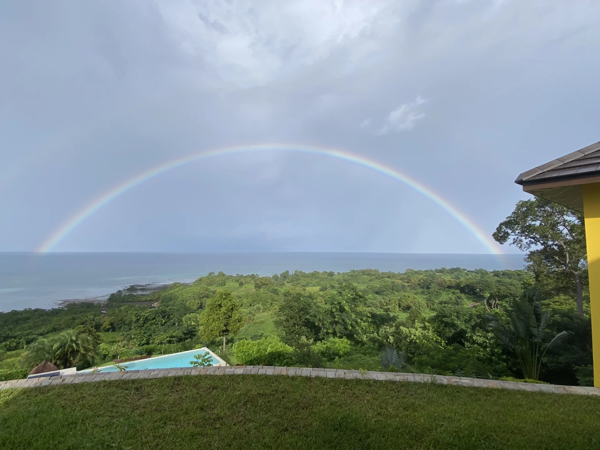 Villa avec vue océan à Nosy Be Vue panoramique sur l'océan avec un arc-en-ciel et un jardin tropical à Nosy Be, Madagascar.