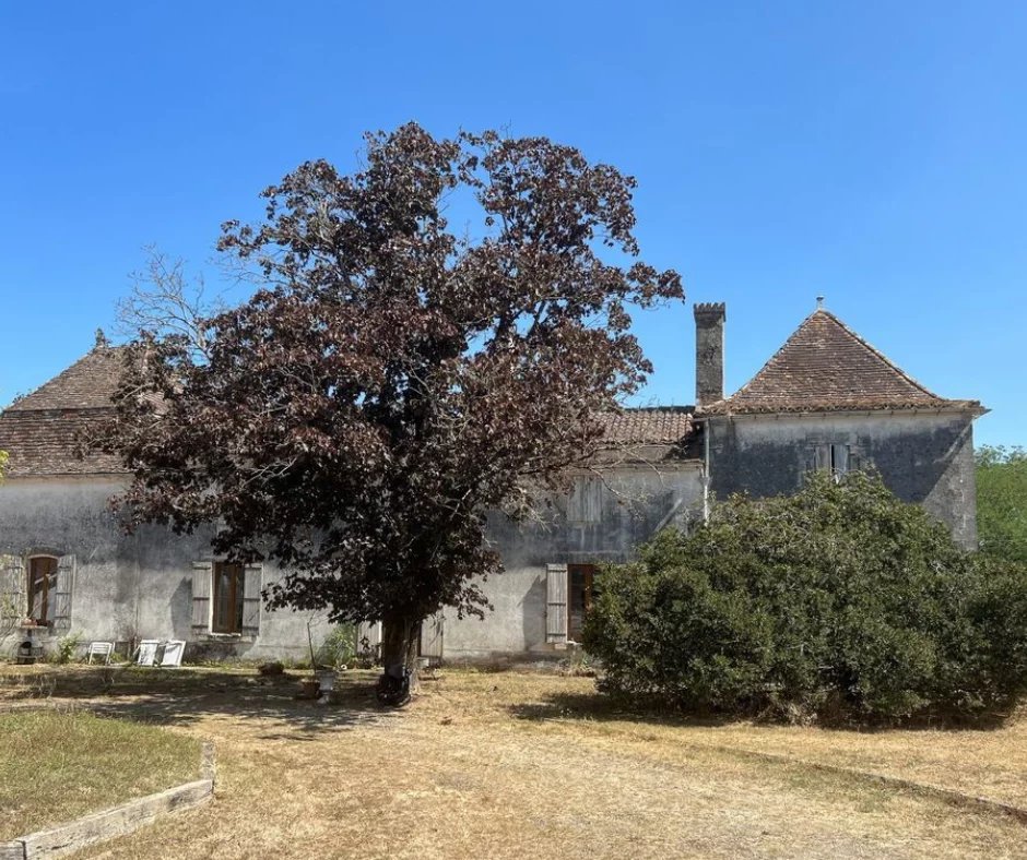 Bâtiment ancien avec un arbre devant, situé sur un domaine équestre à Ménesplet, Dordogne.
