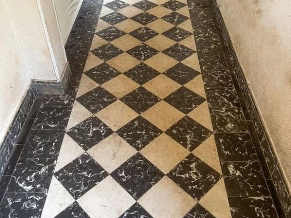 Un couloir avec un sol en carrelage noir et blanc en damier.
