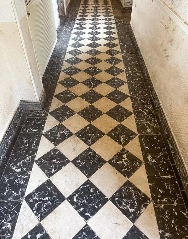 Un couloir avec un sol en carrelage noir et blanc en damier.