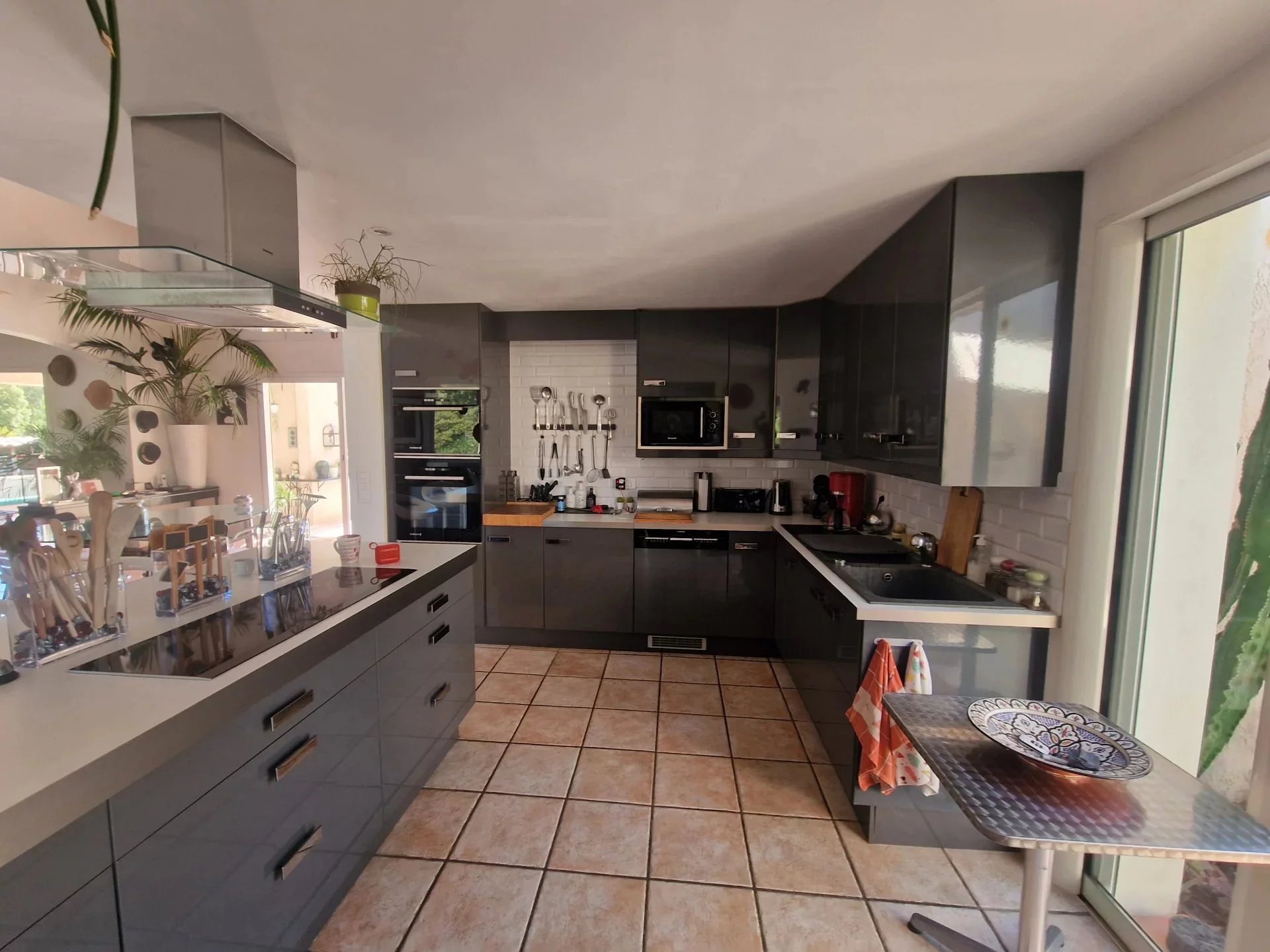 Kitchen of the villa in Marine de Solaro Modern kitchen in a villa in Marine de Solaro, Corsica, with grey furniture and light tiles.