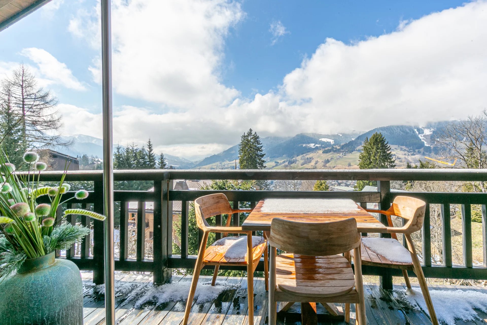 Terrasse avec vue à Megève Terrasse d'un appartement avec vue sur les montagnes à Megève, mobilier en bois et décoration florale.
