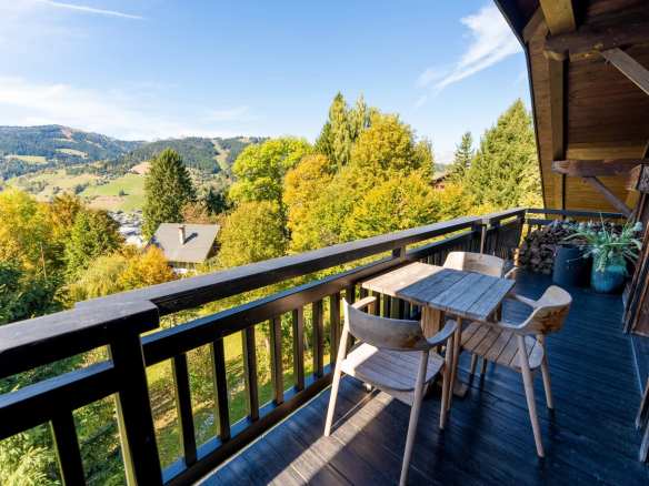 Terrasse d'un appartement avec vue sur la montagne et des chaises en bois à Megève.