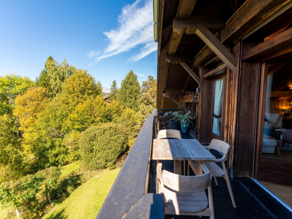 Balcon d'un appartement à Megève avec vue sur la nature environnante et mobilier en bois.