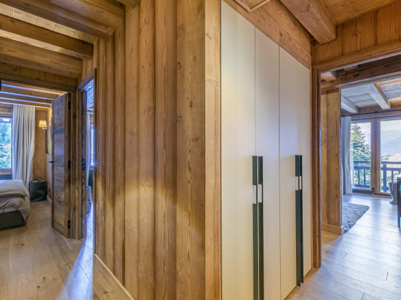 Intérieur d'un appartement en bois à Megève avec couloir et placards.