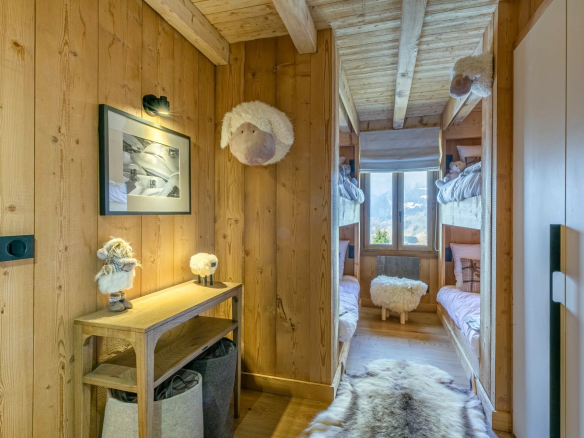 Couloir d'un appartement en bois avec deux lits superposés et décorations en fourrure.