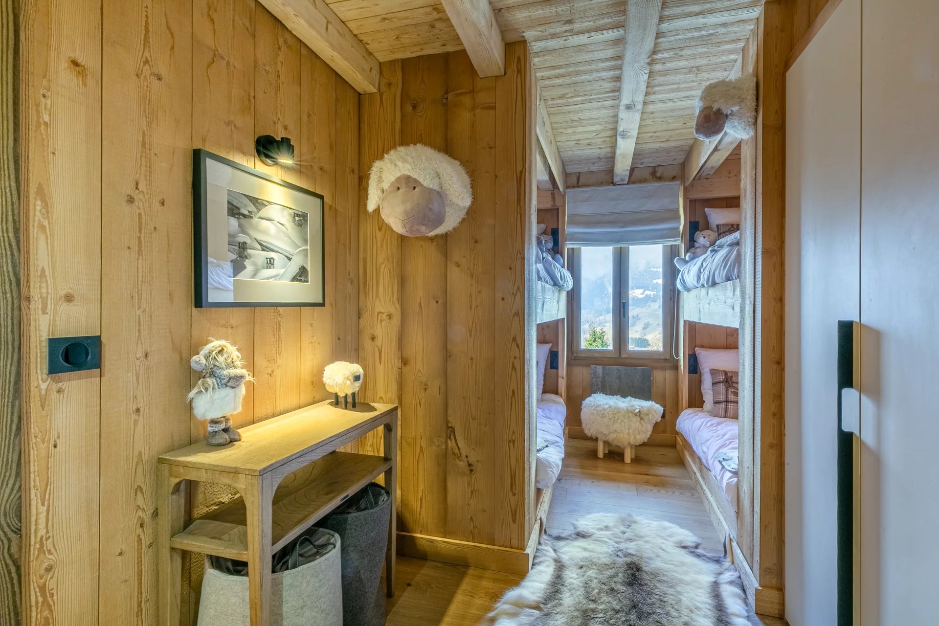 Intérieur d’un appartement à Megève Couloir d'un appartement en bois avec deux lits superposés et décorations en fourrure.