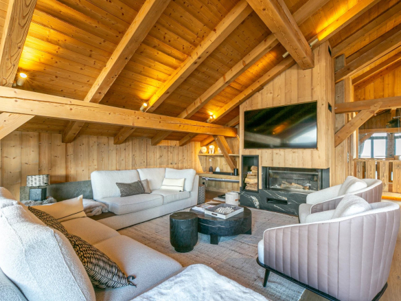 Salon spacieux avec poutres apparentes et cheminée dans un appartement à Megève.