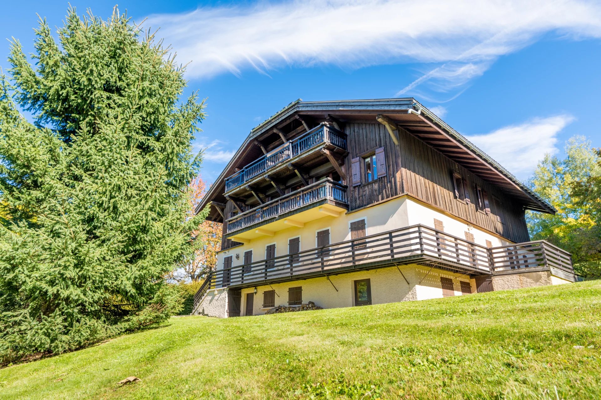 Appartement de prestige à Megève Vue extérieure d'un appartement en bois à Megève avec jardin et arbres.