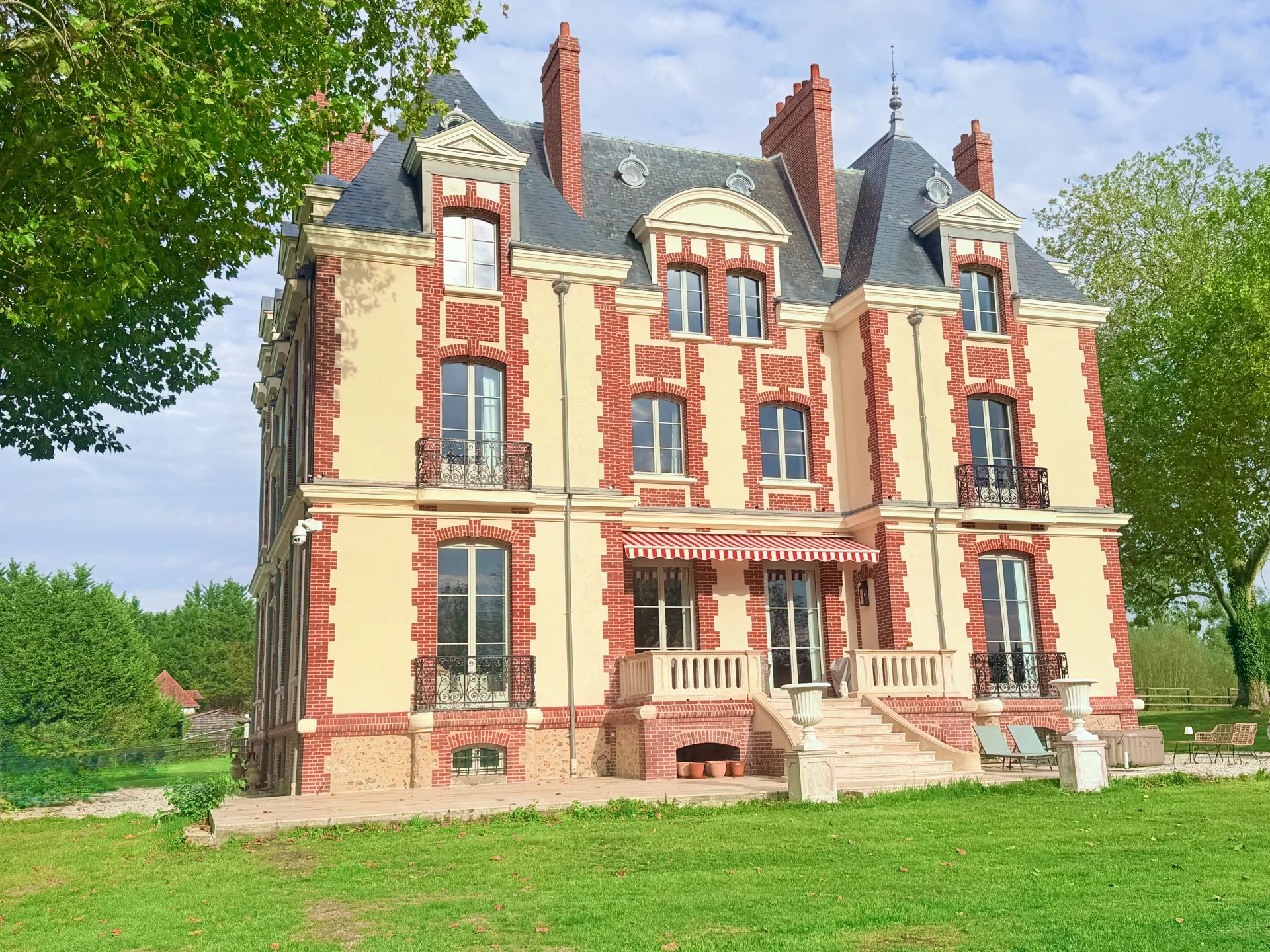 Château équestre de style 1900, 560 m², situé près de Pont-l'Évêque, entouré de verdure.