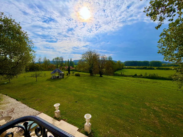 Vue dégagée sur un vaste terrain verdoyant avec un abri de jardin, près de Pont-l'Évêque.