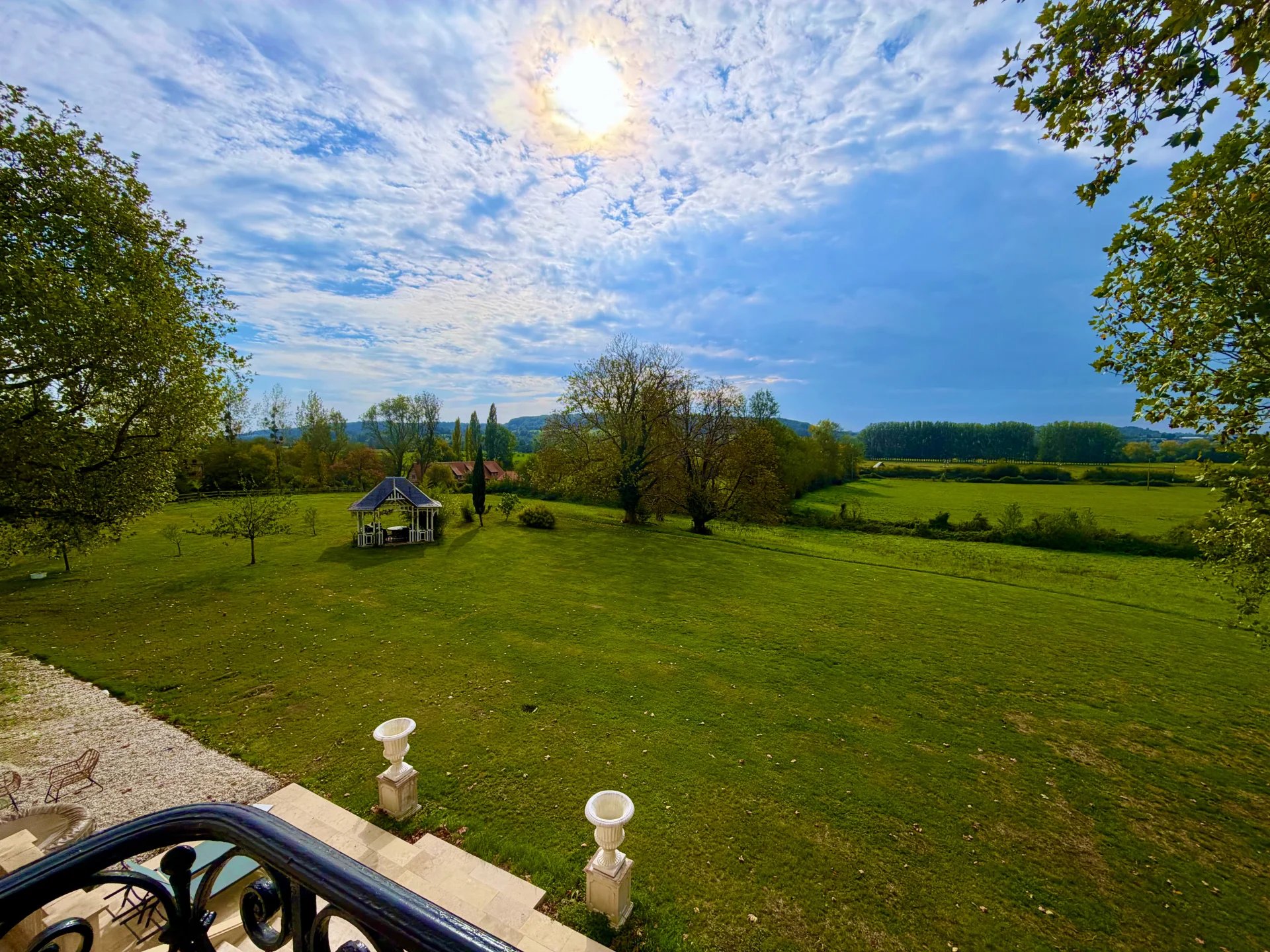 Vue dégagée sur un vaste terrain verdoyant avec un abri de jardin, près de Pont-l'Évêque.