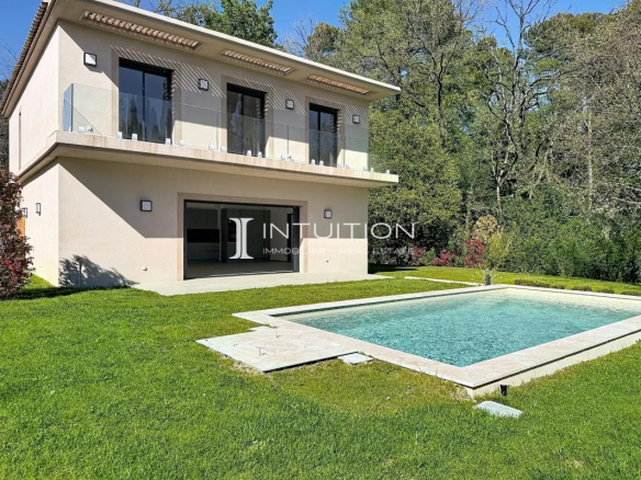 Modern two-story beige house with glass balconies and a rectangular pool in a well-kept backyard.