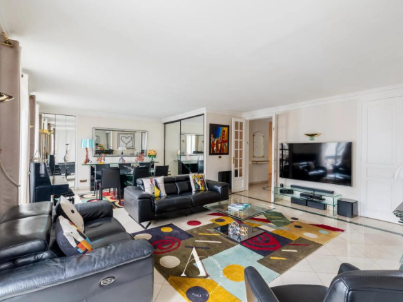 Open-concept living room with black leather sofas, glass coffee table, and a colorful geometric rug facing a wall-mounted TV.
