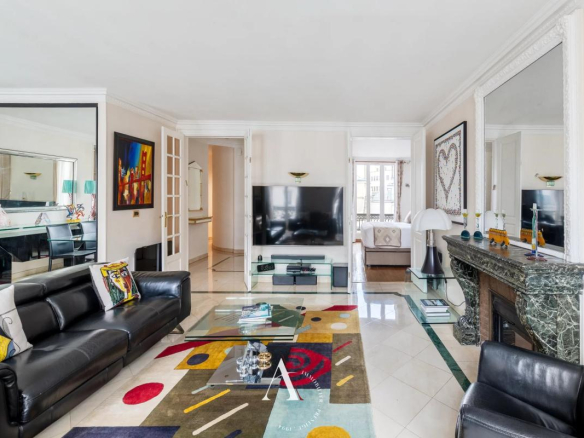 Bright, contemporary living room with black leather sectional, glass coffee table, and a colorful abstract rug.