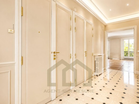 Entrée d'un appartement spacieux avec des portes blanches et un sol en marbre.