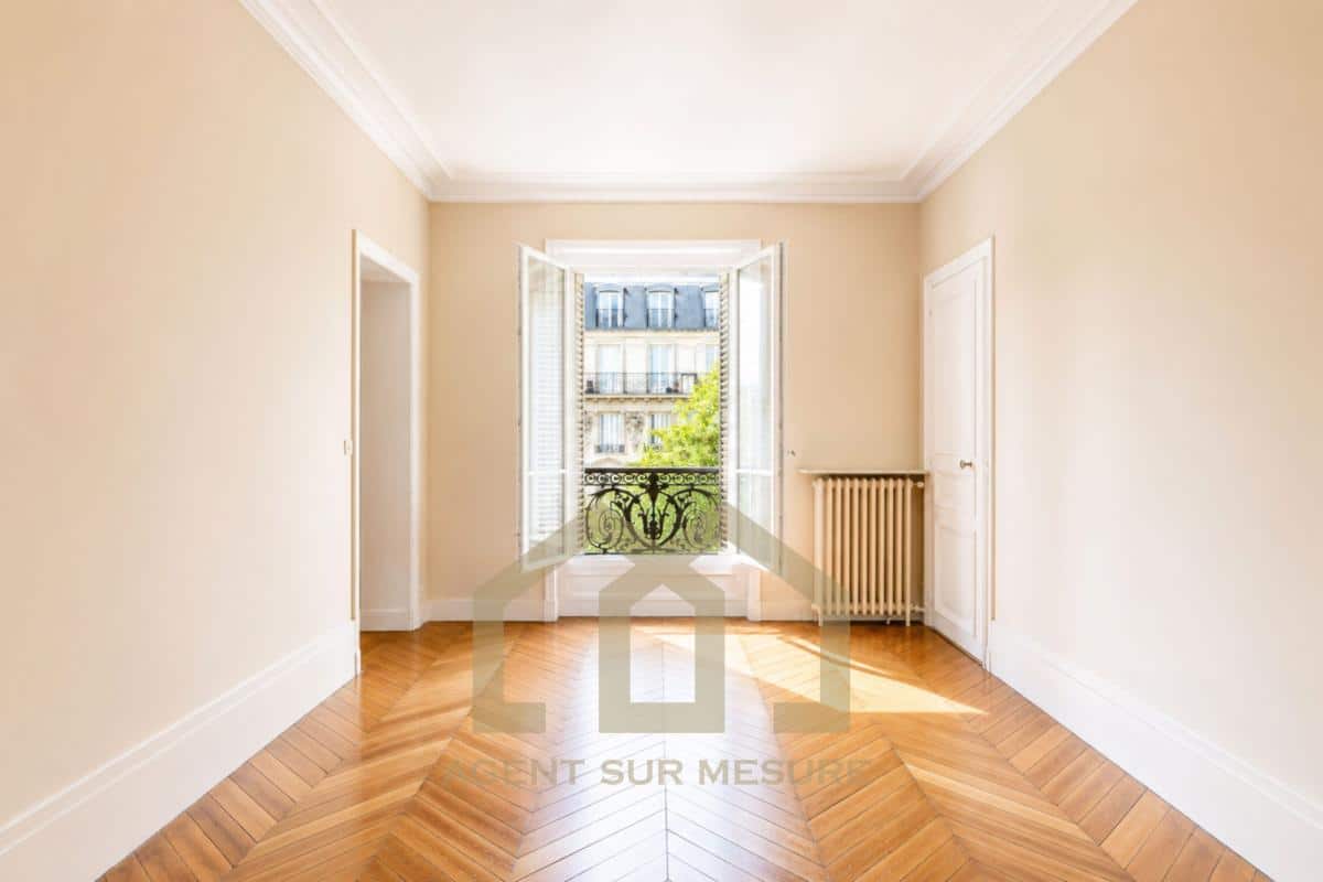 Intérieur d'un appartement de 160 m² avec parquet et fenêtres donnant sur un balcon, Paris 5ème.