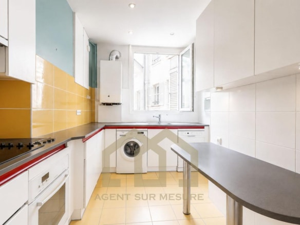 Cuisine moderne avec des éléments en blanc et jaune, fenêtres ouvertes sur l'extérieur.