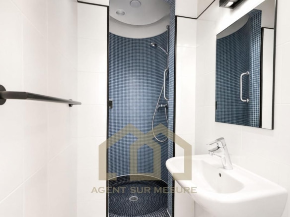 Salle de bain moderne avec douche et lavabo dans un appartement à Paris 5ème.