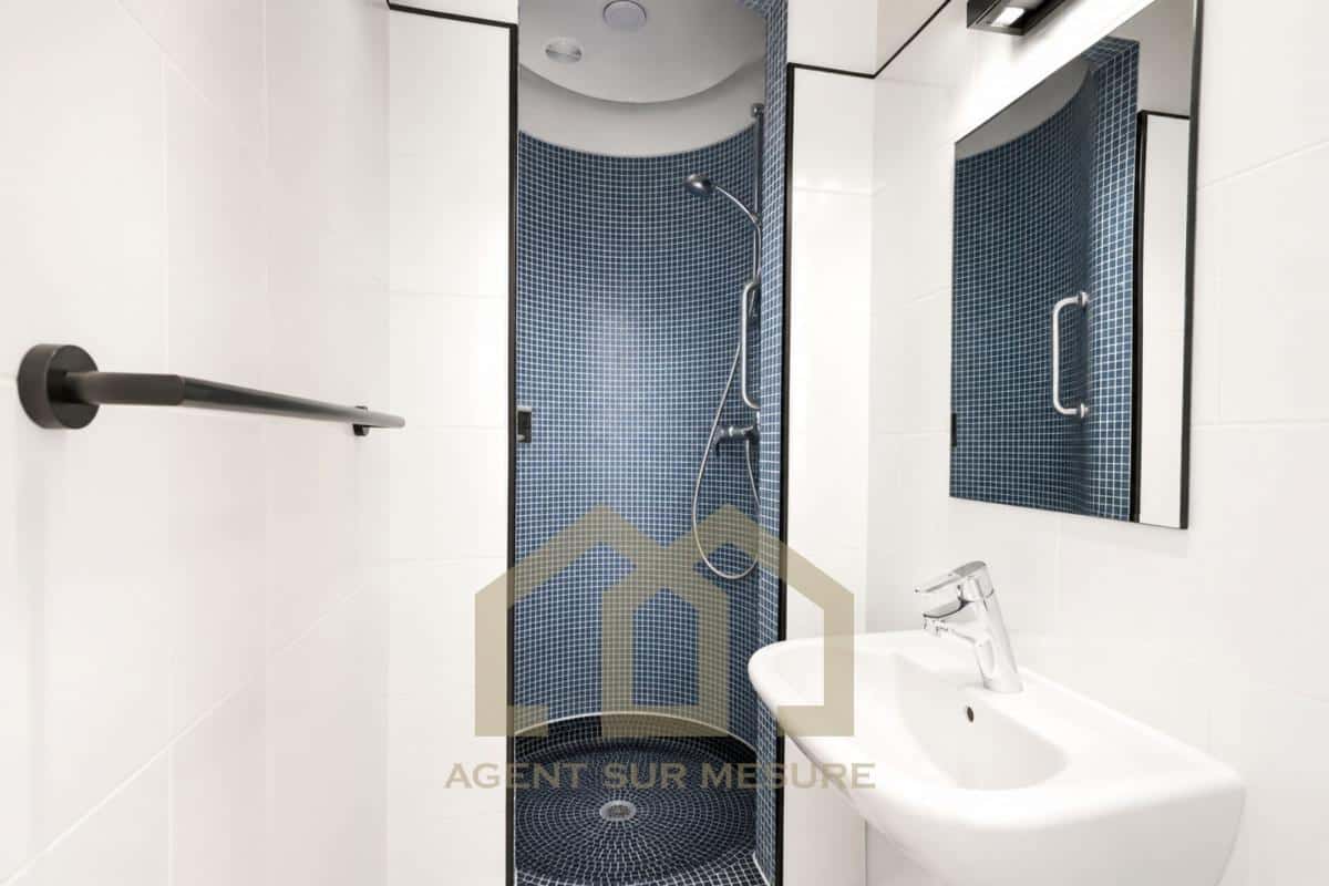Salle de bain moderne avec douche et lavabo dans un appartement à Paris 5ème.